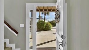 Una puerta que da a un espacio exterior cubierto con vistas a una calle residencial y vegetación.