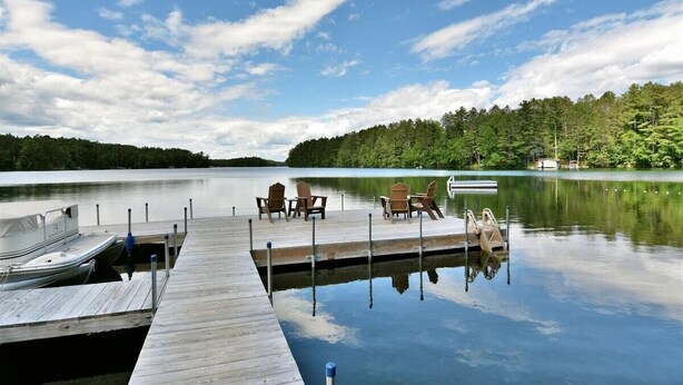 A wooden dock extending into calm water, surrounded by lush greenery and a clear sky. - Virgina Beach #8 on Crystal Clear Lake Owen in Cable,WI (Cable)