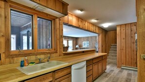 A kitchen with wooden cabinets, a white sink, and a dishwasher. - Virgina Beach #8 on Crystal Clear Lake Owen in Cable,WI (Cable)