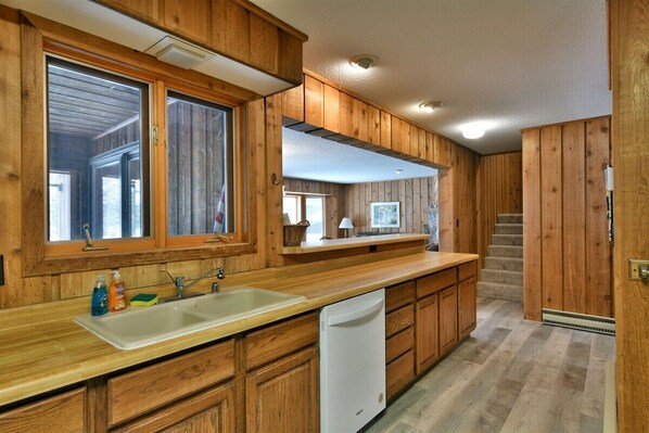A kitchen with wooden cabinets, a white sink, and a dishwasher.