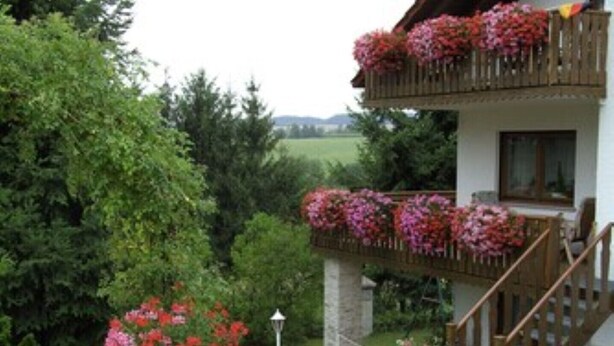 Un edificio de dos pisos con un balcón decorado con flores.