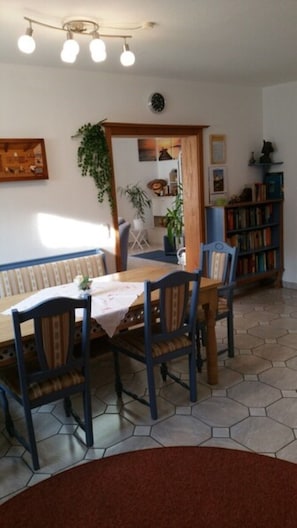 Enjoy meals in this inviting dining area with a bookshelf and views through the archway to another room.