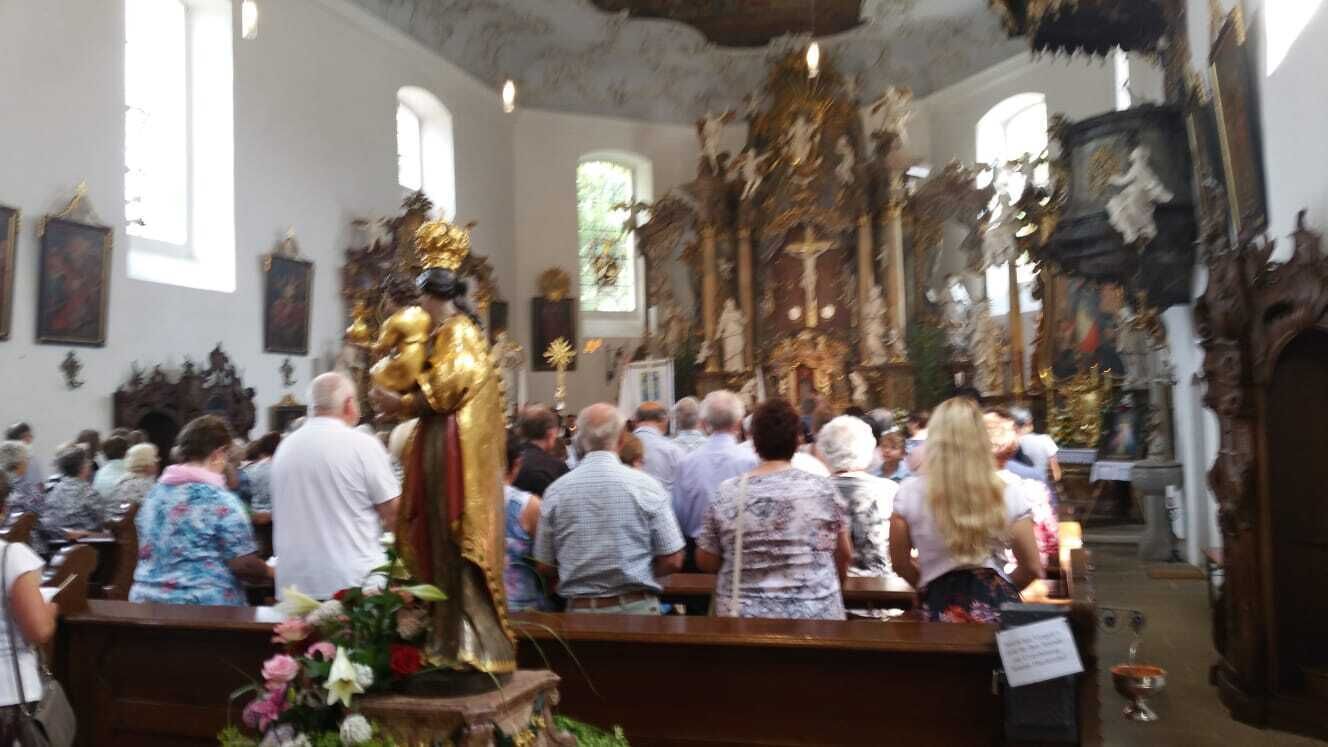Ein Kircheninneres mit einer großen Statue, Kirchenbänken und religiösen Symbolen.