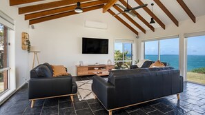 Un salon spacieux avec une grande télévision, deux canapés, une table basse et une vue sur la mer.