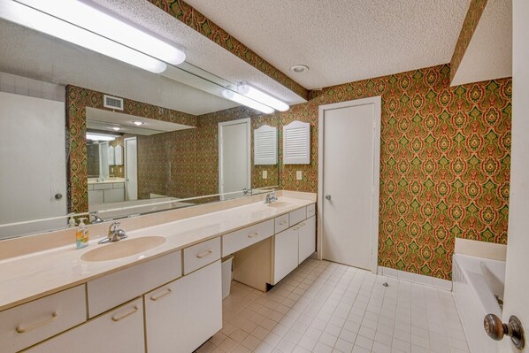 A bathroom with a large mirror, two sinks, and patterned wallpaper.