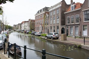 A canal lined with historic buildings, a narrow waterway, and parked cars along the side. - Canal house top floor in historic center Gouda (Gouda)