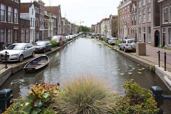 A canal lined with parked cars and traditional buildings. - Canal house top floor in historic center Gouda (Gouda)