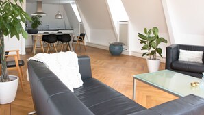 A modern loft apartment with a dining area, a black leather sofa, and a glass coffee table. - Canal house top floor in historic center Gouda (Gouda)