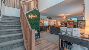 A spacious living area with a staircase, a green wall, and a sign that reads "The Pecan." - Pocono Getaway with Hot Tub, Games & Fire-pit (Tobyhanna)