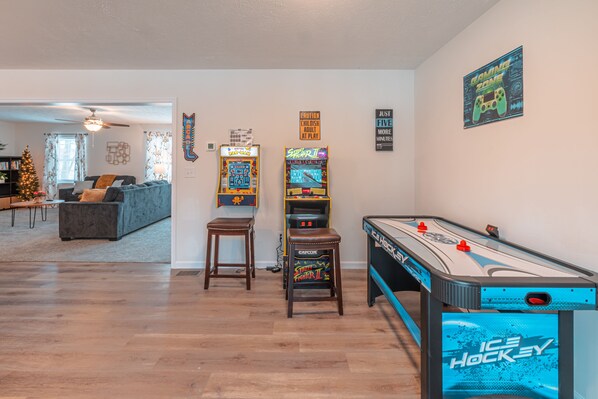 A living room with a pool table, two arcade games, a Christmas tree, and a sofa. - Pocono Getaway with Hot Tub, Games & Fire-pit (Tobyhanna)
