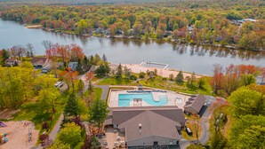An aerial view of a resort with a swimming pool, parking area, and surrounding forested landscape. - Pocono Getaway with Hot Tub, Games & Fire-pit (Tobyhanna)