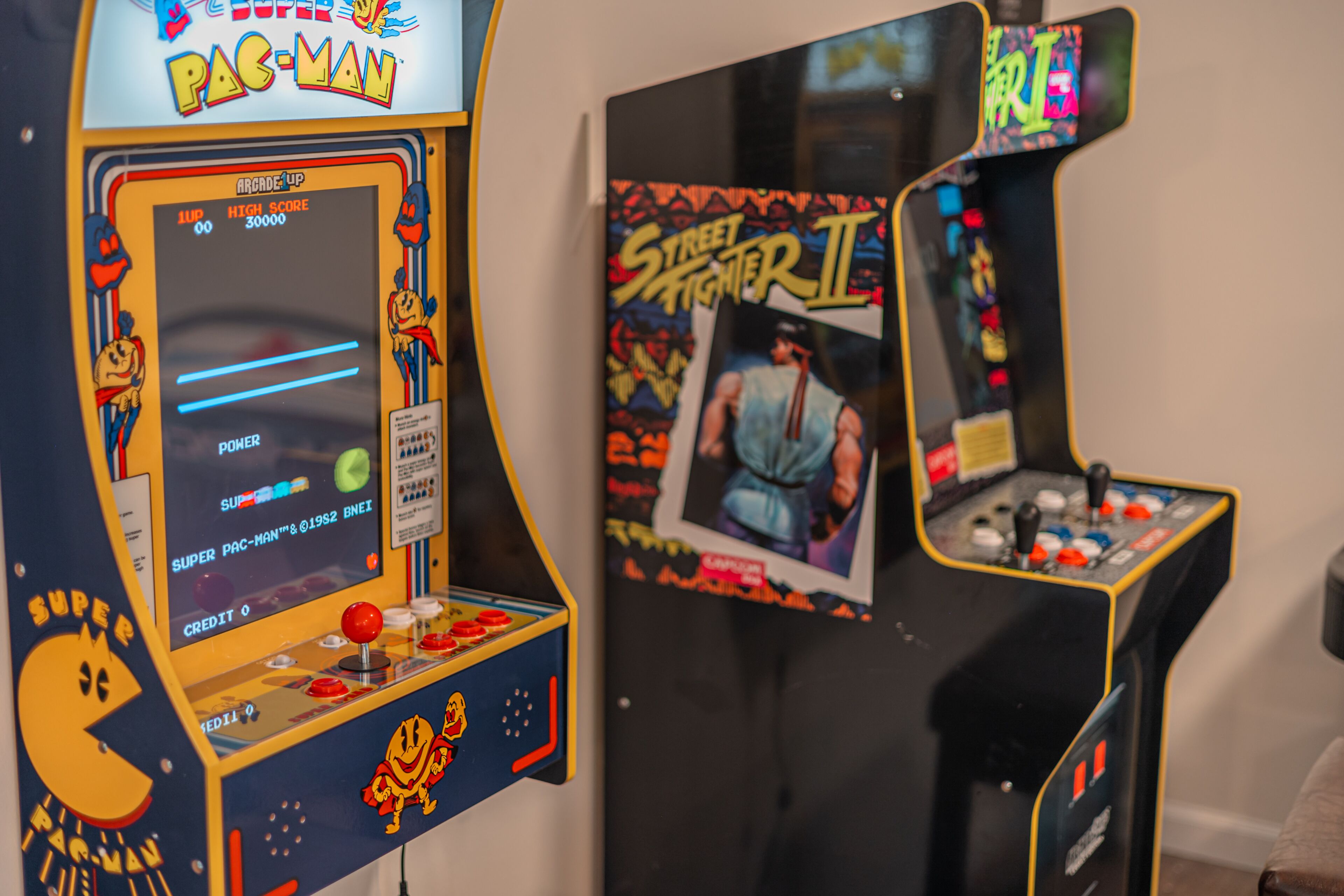 Arcade machines, including a Pac-Man and Street Fighter II, in a room.
