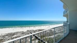 A balcony with a view of a beach and the ocean.