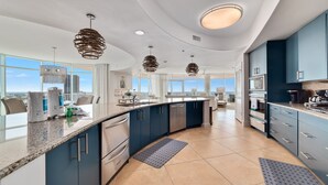 A modern kitchen with a curved island, stainless steel appliances, and blue cabinetry.