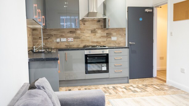 A modern kitchen with grey cabinets, a gas stove, and a built-in oven. - Albany Apartments (Portsmouth)