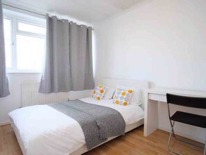 A bedroom with a bed, a desk, and a chair. - Albany Apartments (Portsmouth)