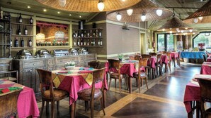 Un restaurante con mesas y sillas de madera, una zona de bar con botellas, y vistas al exterior.