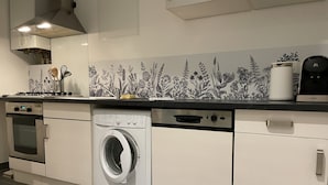 A modern kitchen with a built-in washing machine, a coffee maker, and a gas stove.