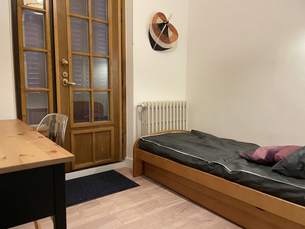A room with a wooden bed, a small table, and a chair.