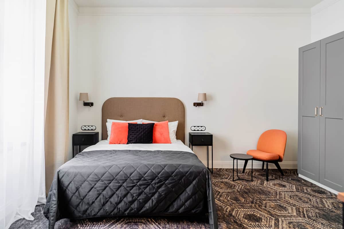 Een hotelkamer met een bed, twee nachtkastjes, een stoel en een kledingkast.