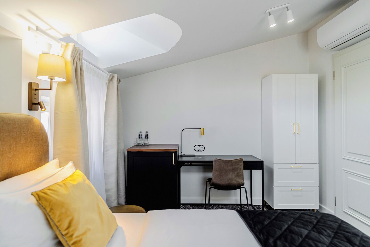 Une chambre d’hôtel comprenant un lit, un bureau, une chaise, une armoire et une lampe.