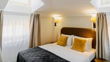Een hotelkamer met een bed, gordijnen, een nachtkastje en een wandlamp.