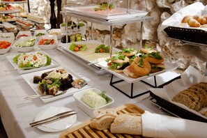 Un buffet proposant une variété de plats, notamment des sandwichs, des salades et du pain.