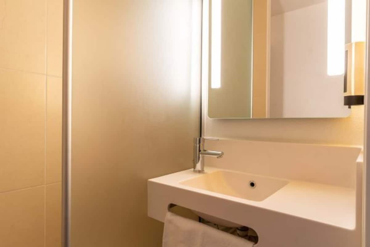 A bathroom with a white sink, a mirror, and a towel hanging on a rack.