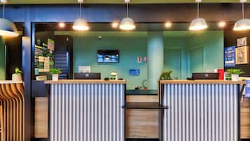 A reception area with two counters, a television screen, and a wall with informational posters.