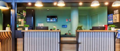 A reception area with two counters, a television screen, and a wall with informational posters.