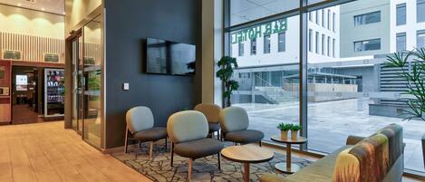 A hotel lobby with seating, a TV, and large windows.