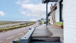 A modern building with a wooden deck and a paved road in the background. - Dunefront Apartment - A perfect getaway location! (Zandvoort)