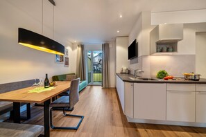 A modern kitchen with a dining area, wooden flooring, and a view to the outside.