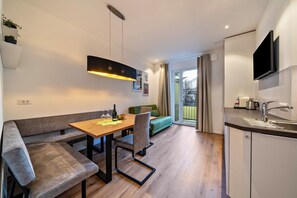 Une cuisine moderne avec un coin repas, un four encastré et un téléviseur à écran plat fixé au-dessus du plan de travail.