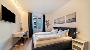 Un dormitorio con cama, escritorio y televisión.