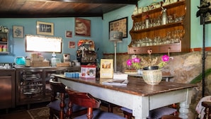 A rustic kitchen with wooden cabinets, a stone wall, and a wooden dining table with chairs.