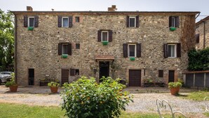 A stone building with multiple windows, a door, and potted plants in the foreground.