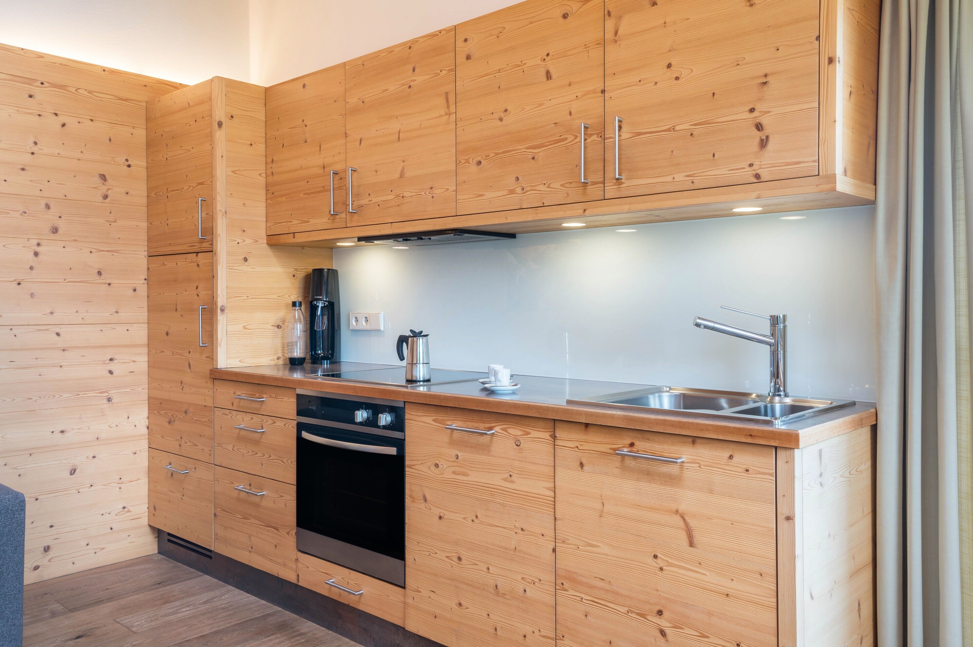 A modern kitchen with wooden cabinets, stainless steel appliances, and a built-in oven.