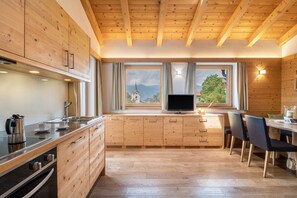 A modern kitchen with wooden cabinets, a built-in oven, and a dining area with chairs.