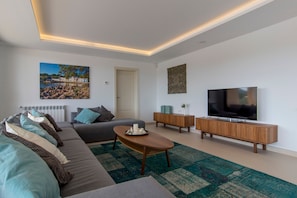 Ein modernes Wohnzimmer mit einer Couch, einem Couchtisch, einem Fernseher und Kunstwerken an den Wänden.