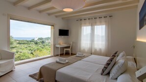A bedroom with a bed, a desk, a chair, a TV, and a view of the outdoors.