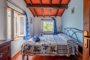 Un dormitorio con una cama, una ventana, una mesita de noche y un aparador de madera.