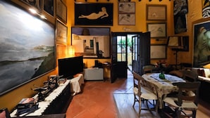 A room with a large painting, a television, a table with chairs, and a door leading to another room. - Apartment 'Navila Número 3' with Shared Pool, Wi-Fi and Air Conditioning (Eivissa)