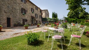 Un patio con edificios de piedra, mobiliario exterior y plantas en macetas.