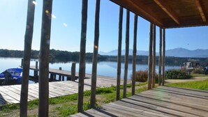 A wooden deck with a view of a calm lake and distant mountains. - Luxury villa -private heated pool-mountain view 5 min from the sea-4 bdrms -2SDB (Serra-di-Fiumorbo (20243))