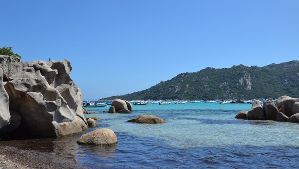 A coastal landscape with large rocks, clear turquoise water, and boats in the distance. - Luxury villa -private heated pool-mountain view 5 min from the sea-4 bdrms -2SDB (Serra-di-Fiumorbo (20243))