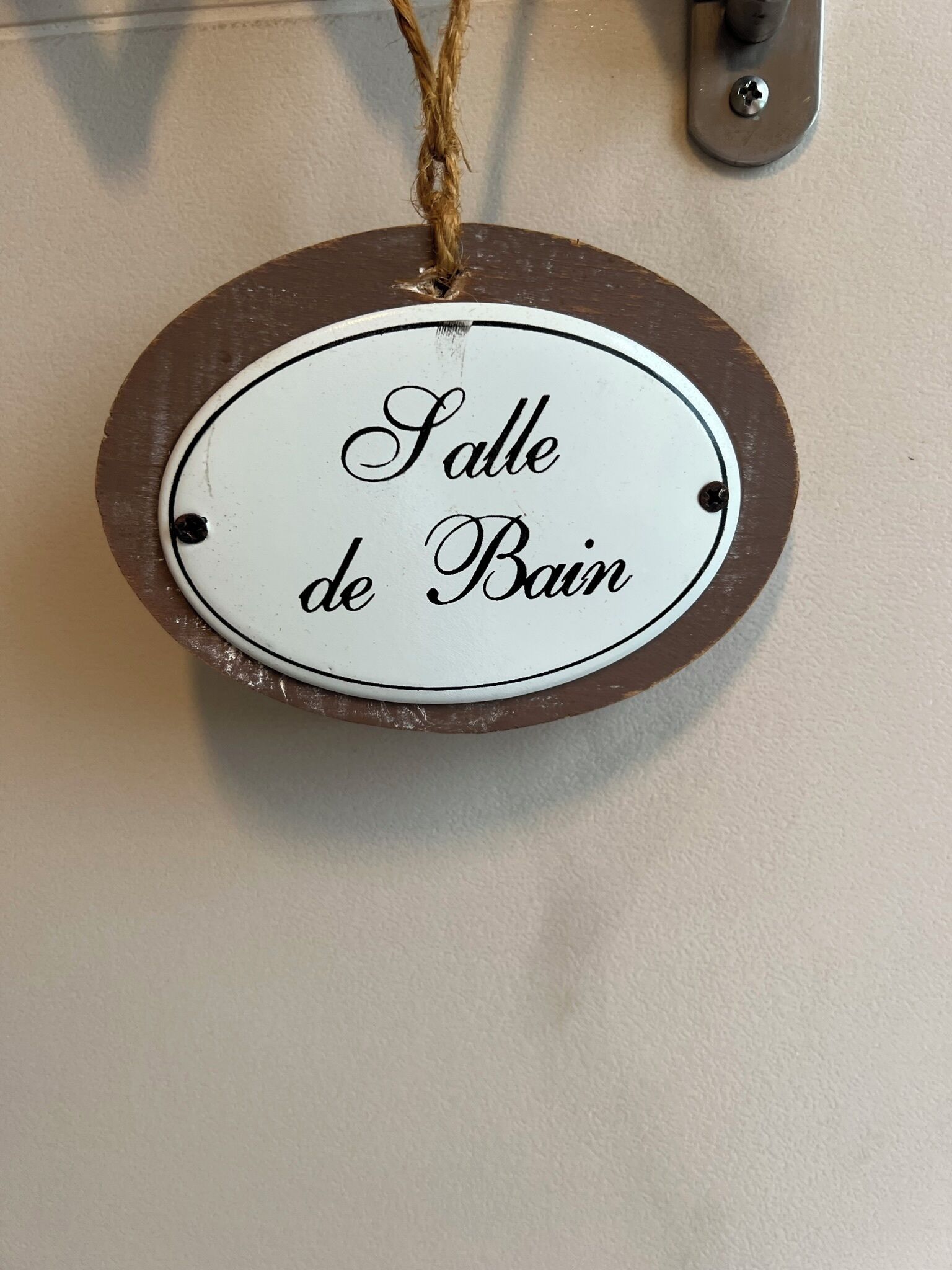 Ein Holzschild mit dem Schriftzug 'Salle de Bain' an einer Wand.