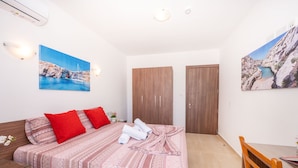 Quarto com uma cama, guarda-roupa de madeira, escrivaninha e duas pinturas.