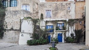 A narrow cobblestone street with buildings featuring stone walls, blue doors, and green windows. - Apartment 'Navila Numero 2' with Shared Pool, Wi-Fi and Air Conditioning (Eivissa)