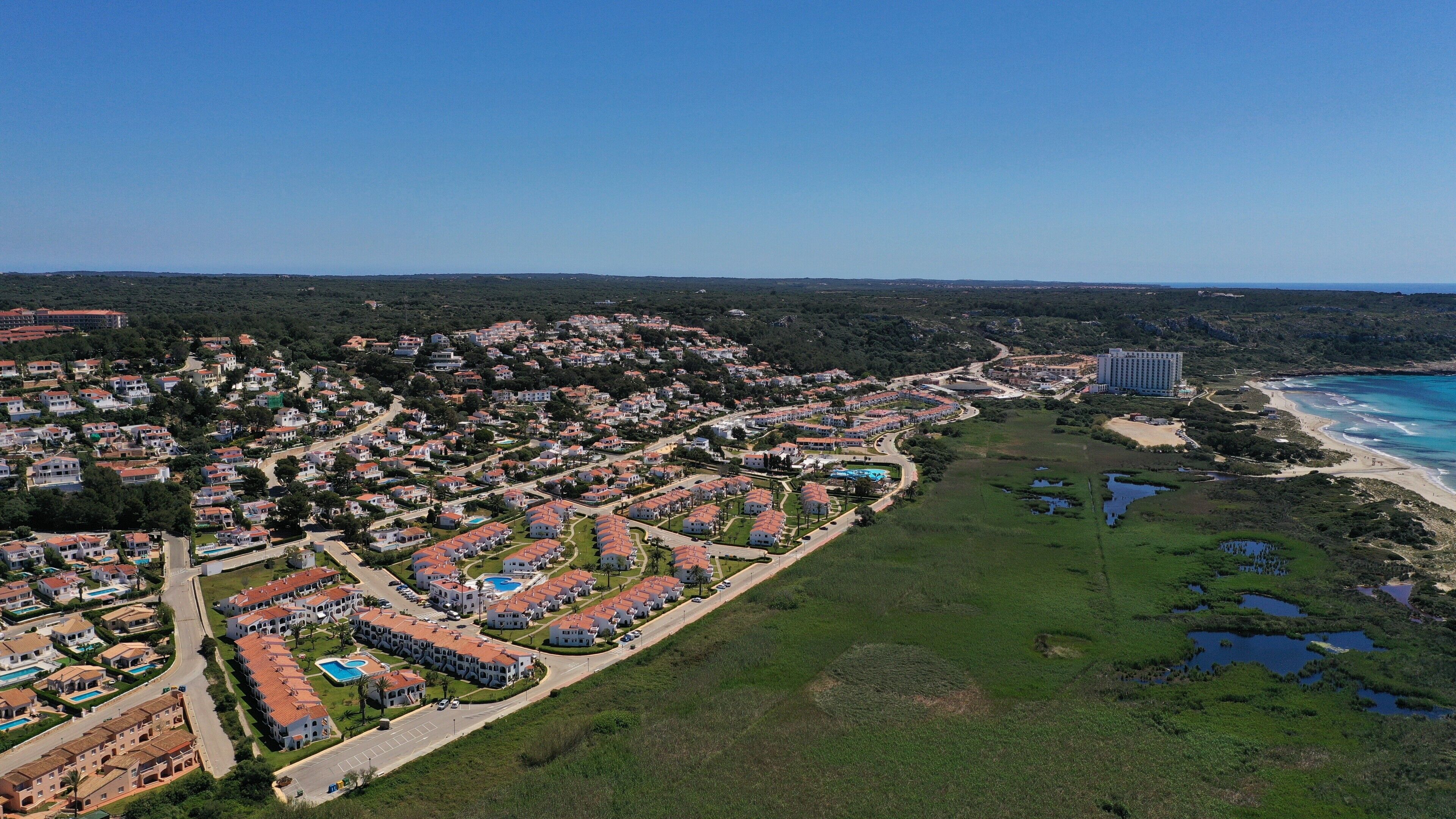 A coastal resort with multiple buildings, a beach, and a large hotel.